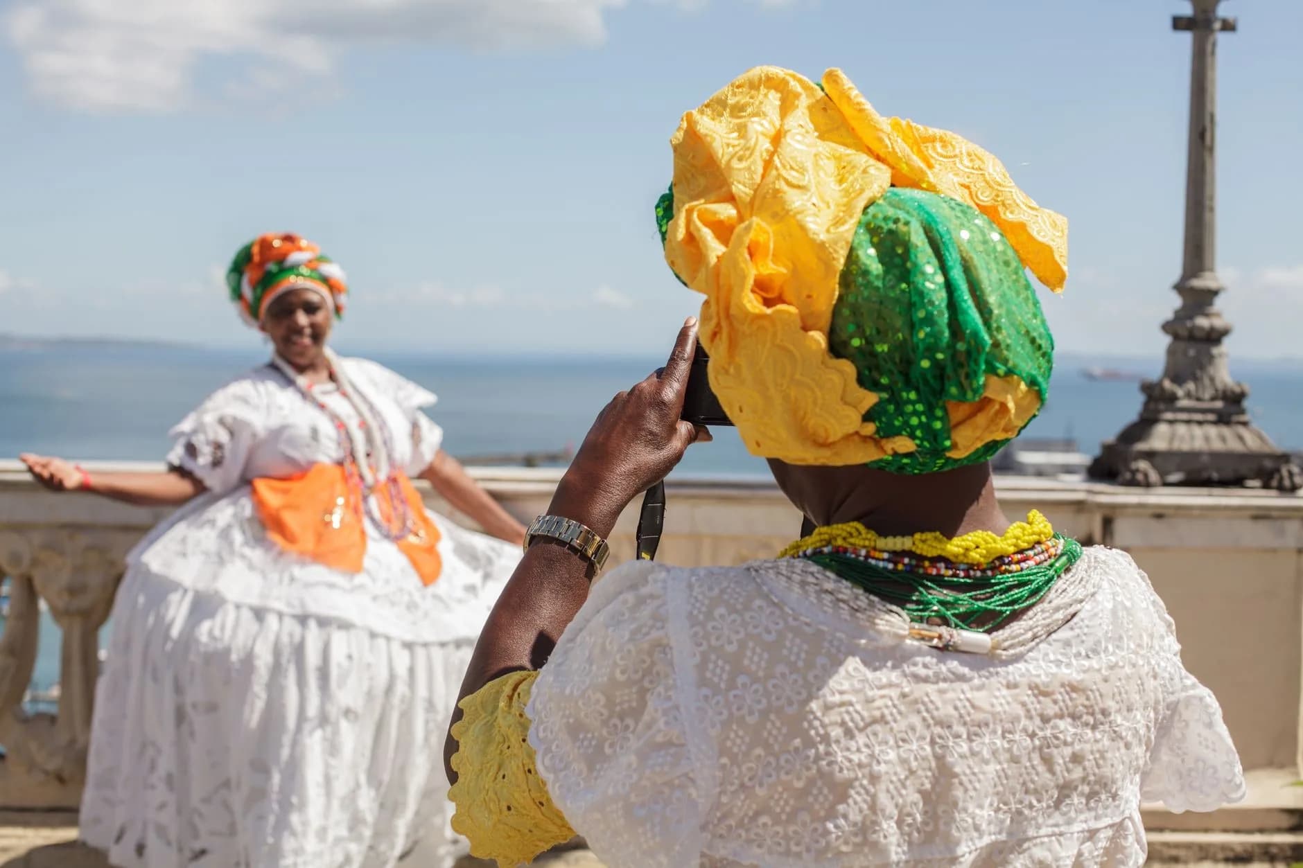 Women in traditional Bahian dress posing for photos in sunny Salvador, Brazil.