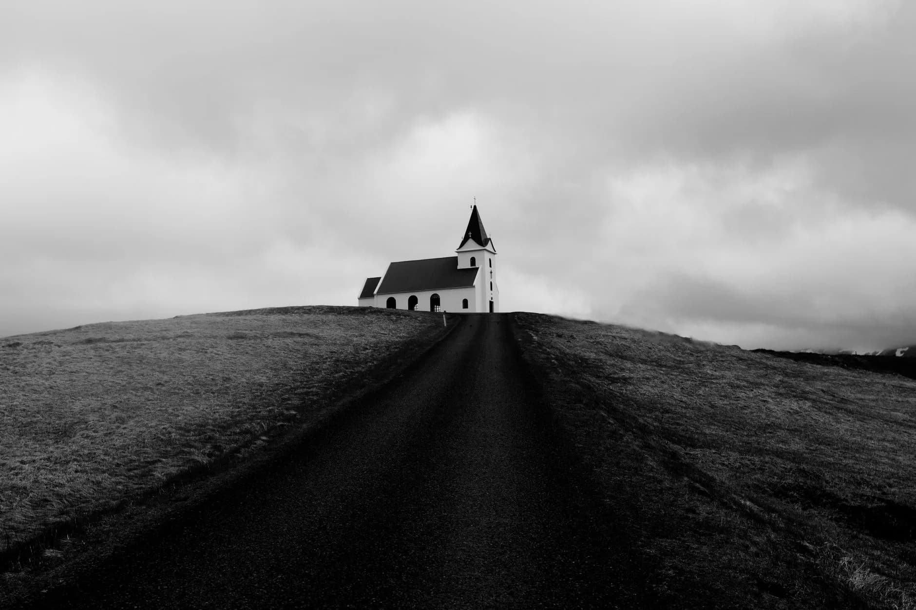 A solitary church atop a hill in Iceland set against a dramatic cloudy sky in black and white.